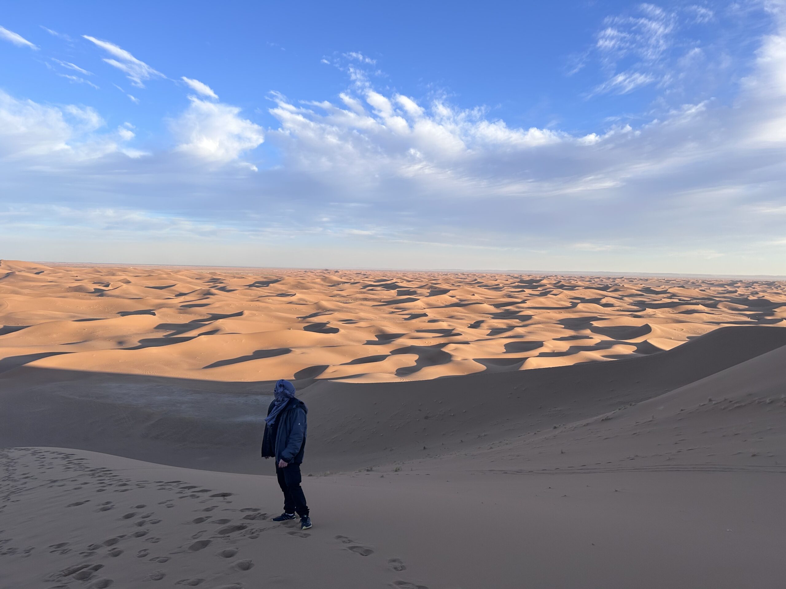 Randonneur face aux dunes du Sahara marocain au lever du soleil