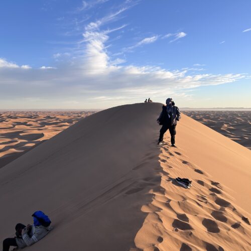 Groupe de voyageurs sur une crête de dune au lever du soleil