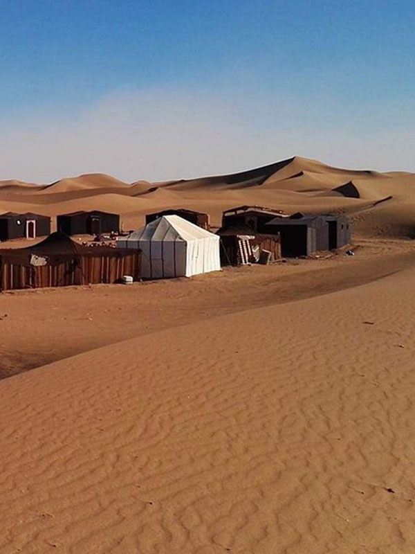 Camp sauvage berbère à l'Erg Zahar sous un ciel étoilé, désert marocain